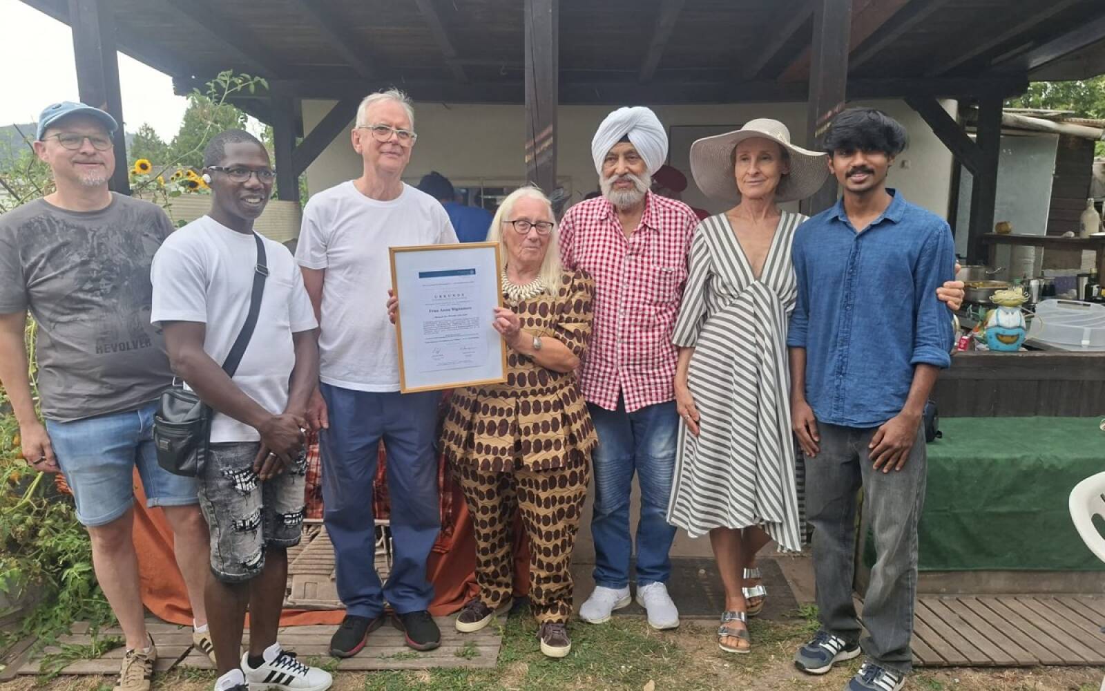 Anna Bignamou (Mitte) zeigt beim Gartenfest der Deutsch-Indischen Gesellschaft Trier die Urkunde zur Auszeichnung als „Mensch des Monats“ Juli 2026. Foto: DIG Trier