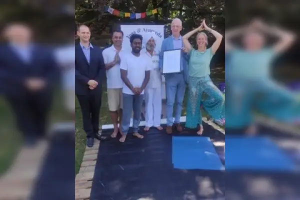 Ehrengäste und Organisatoren des Weltyogafestivals vor dem Banner von Purnima Yoga & Ayurveda, einer der Anwesenden hält eine Urkunde in den Händen. Foto: DIG Trier e.V. [OFFEN: Personen zuordnen]