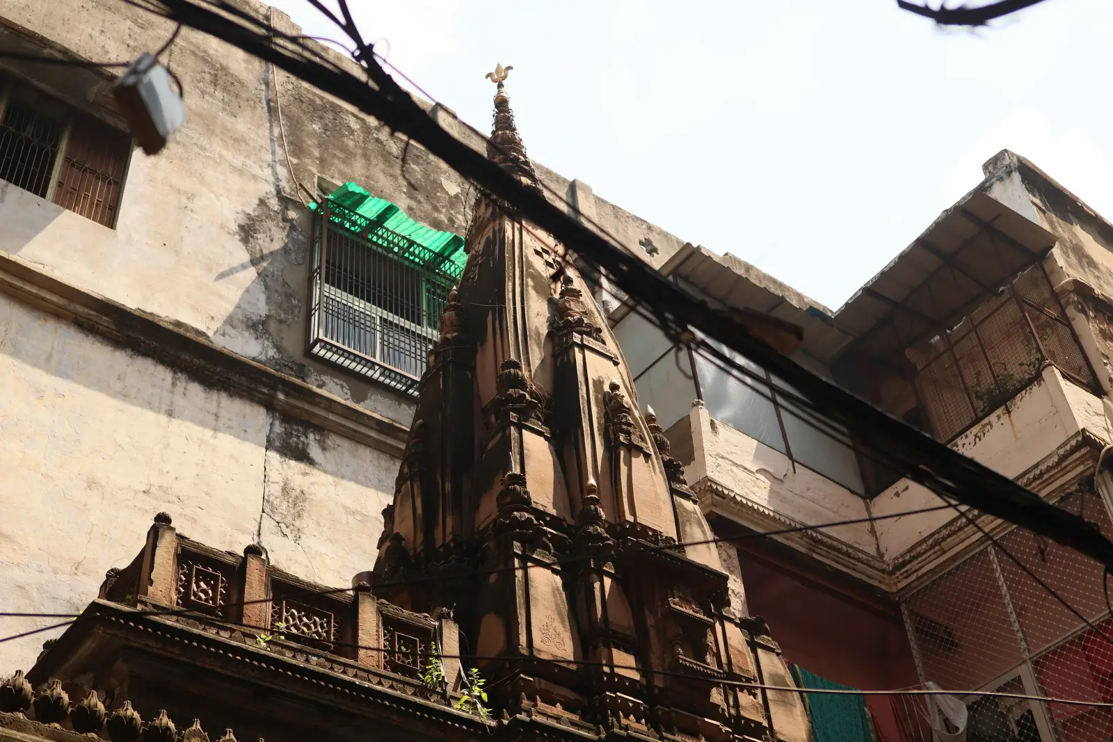 Ein Tempelturm ragt zwischen Wohnhäusern und Stromkabeln in der Altstadt von Varanasi auf. Foto: privat